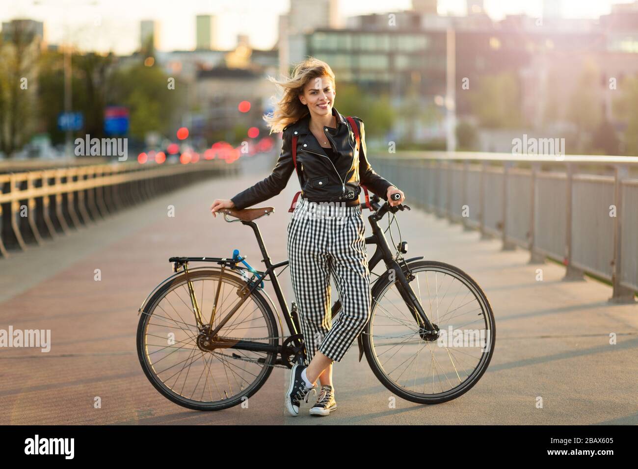 Giovane donna con bicicletta al tramonto Foto Stock