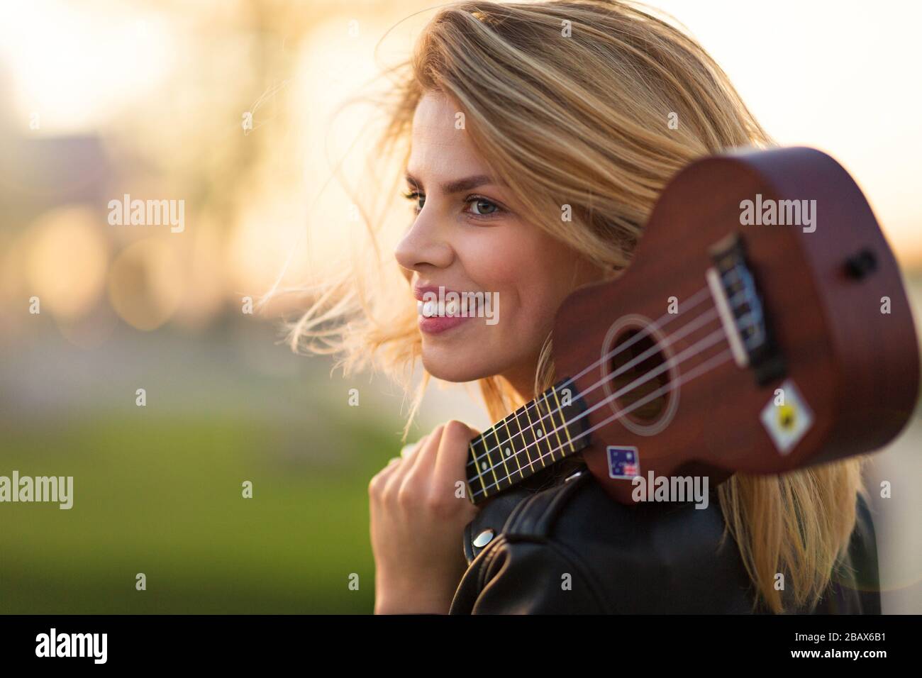 Bella donna con chitarra al tramonto Foto Stock