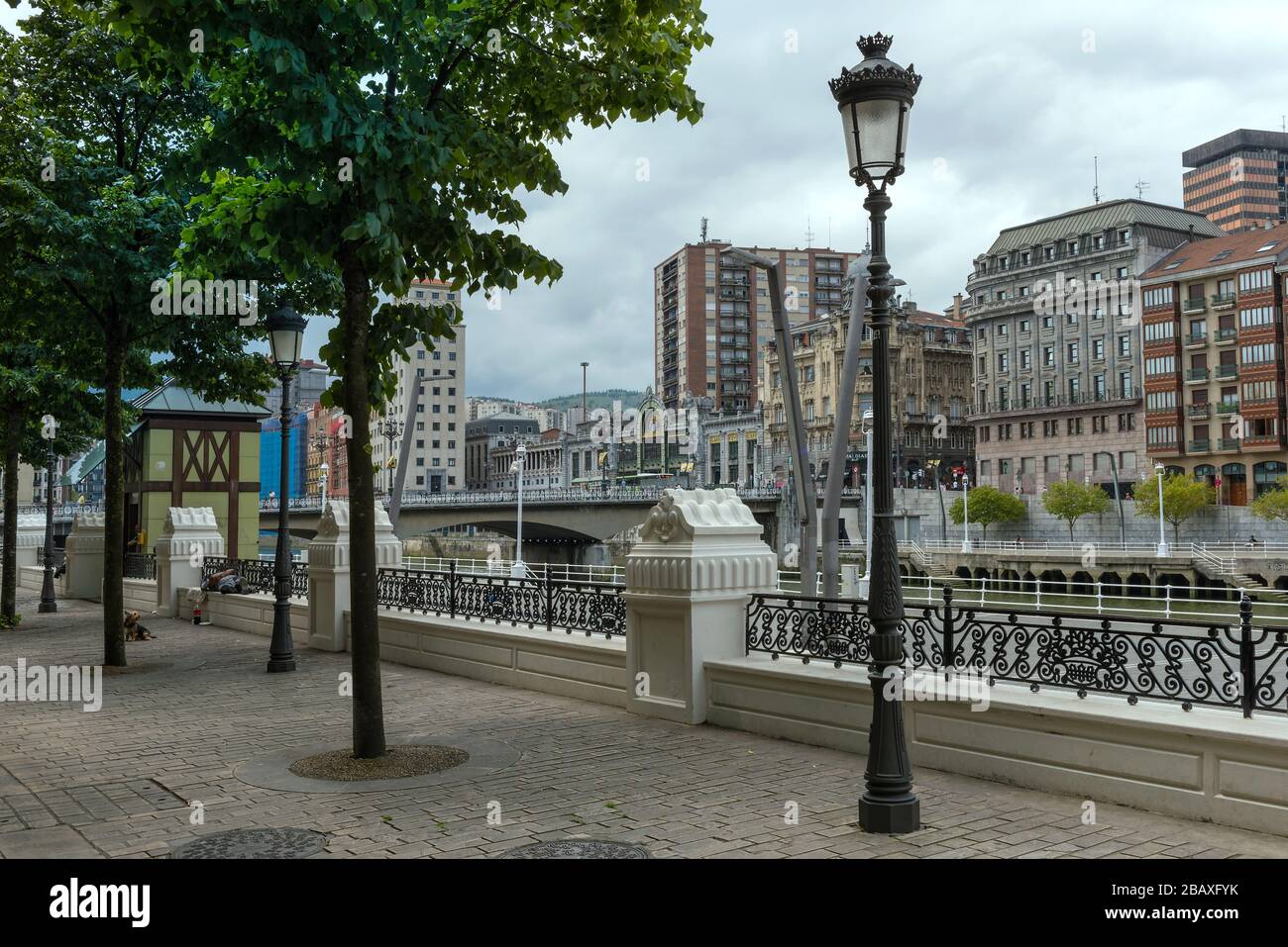 Passeggiata sul fiume Nervion con il Ponte Arenal e la stazione ferroviaria Bilbao-Abando Foto Stock