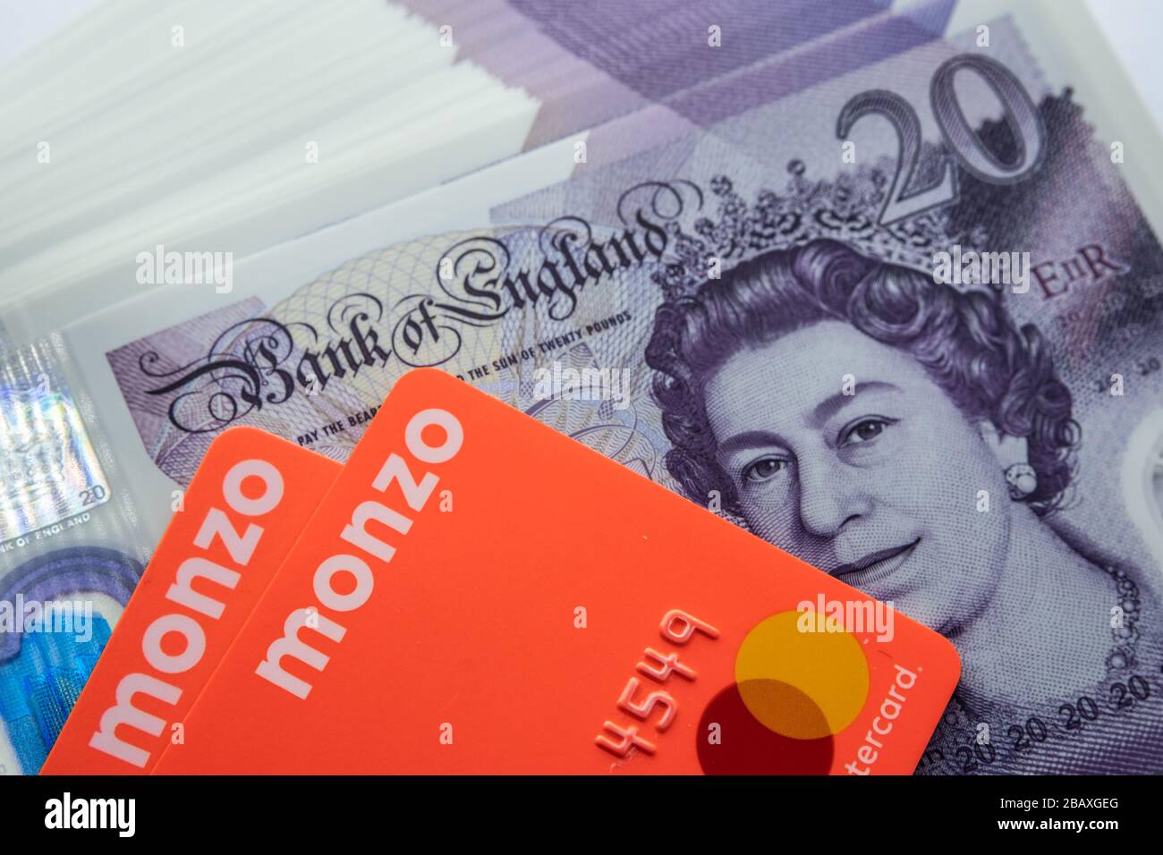 Carte bancarie Monzo collocate sopra le nuove banconote in polimero da 20 libbre. Chiudi la foto. Foto Stock