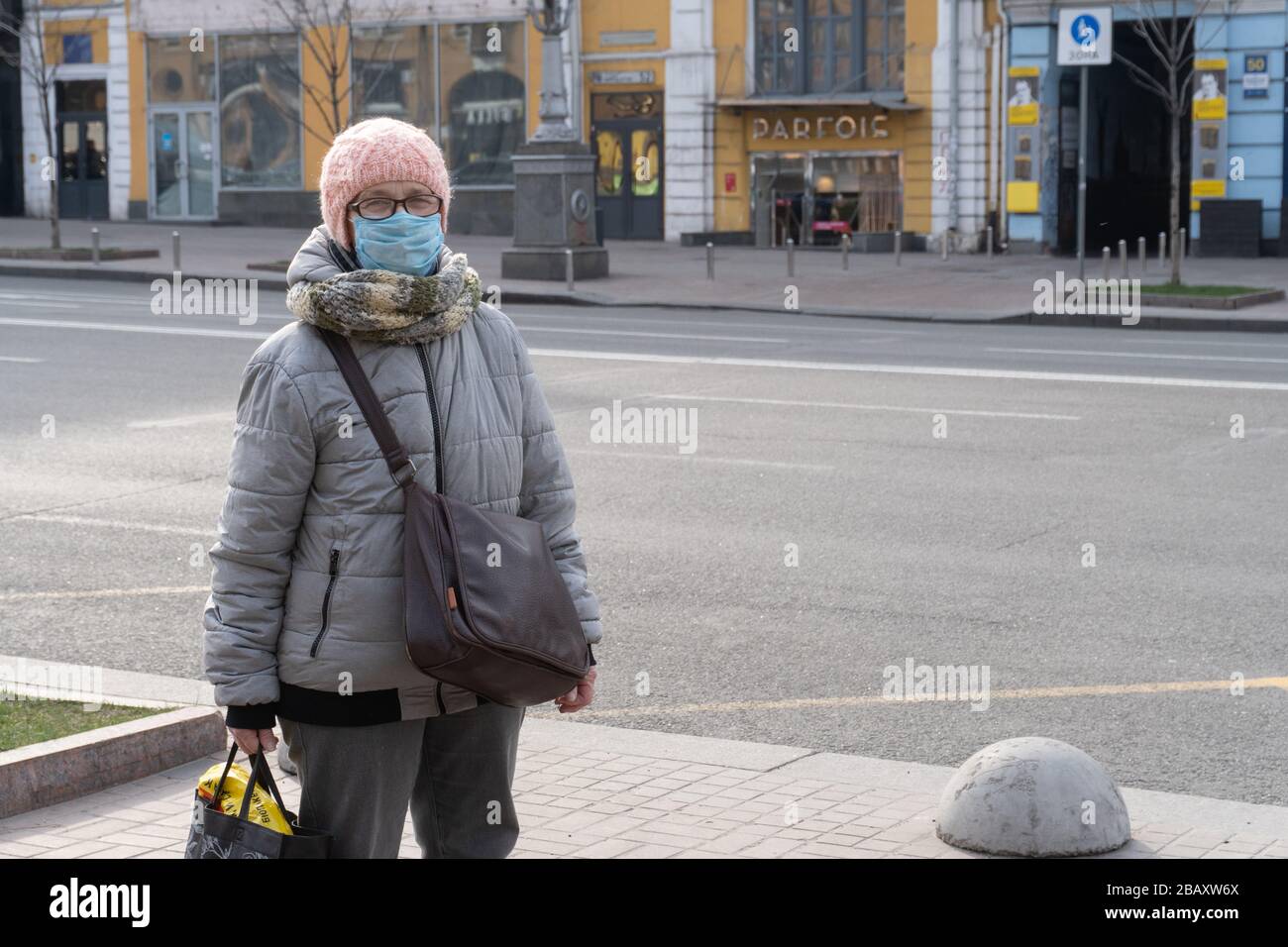 Kiev, Ucraina, 27 marzo 2020, Elder ukranian donna in maschera facciale di protezione rimane sulla strada Foto Stock