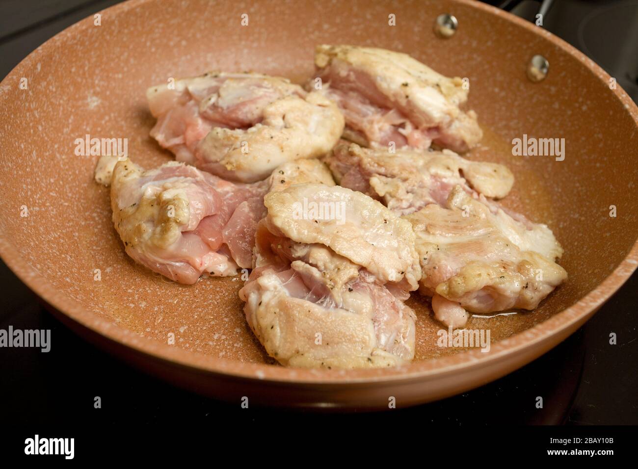 Friggere le cosce di pollo in padella sul piano cottura Foto Stock