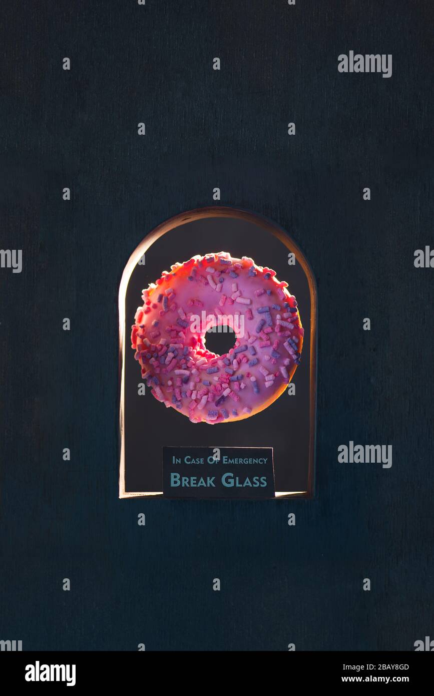 Ciambella con smalto rosa in una nicchia nera con testo in caso di rottura di emergenza Foto Stock