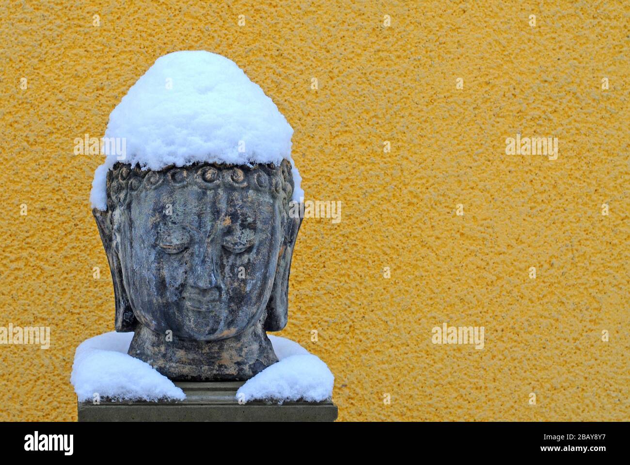 Statua di Buddha con cappello e collare innevati Foto Stock