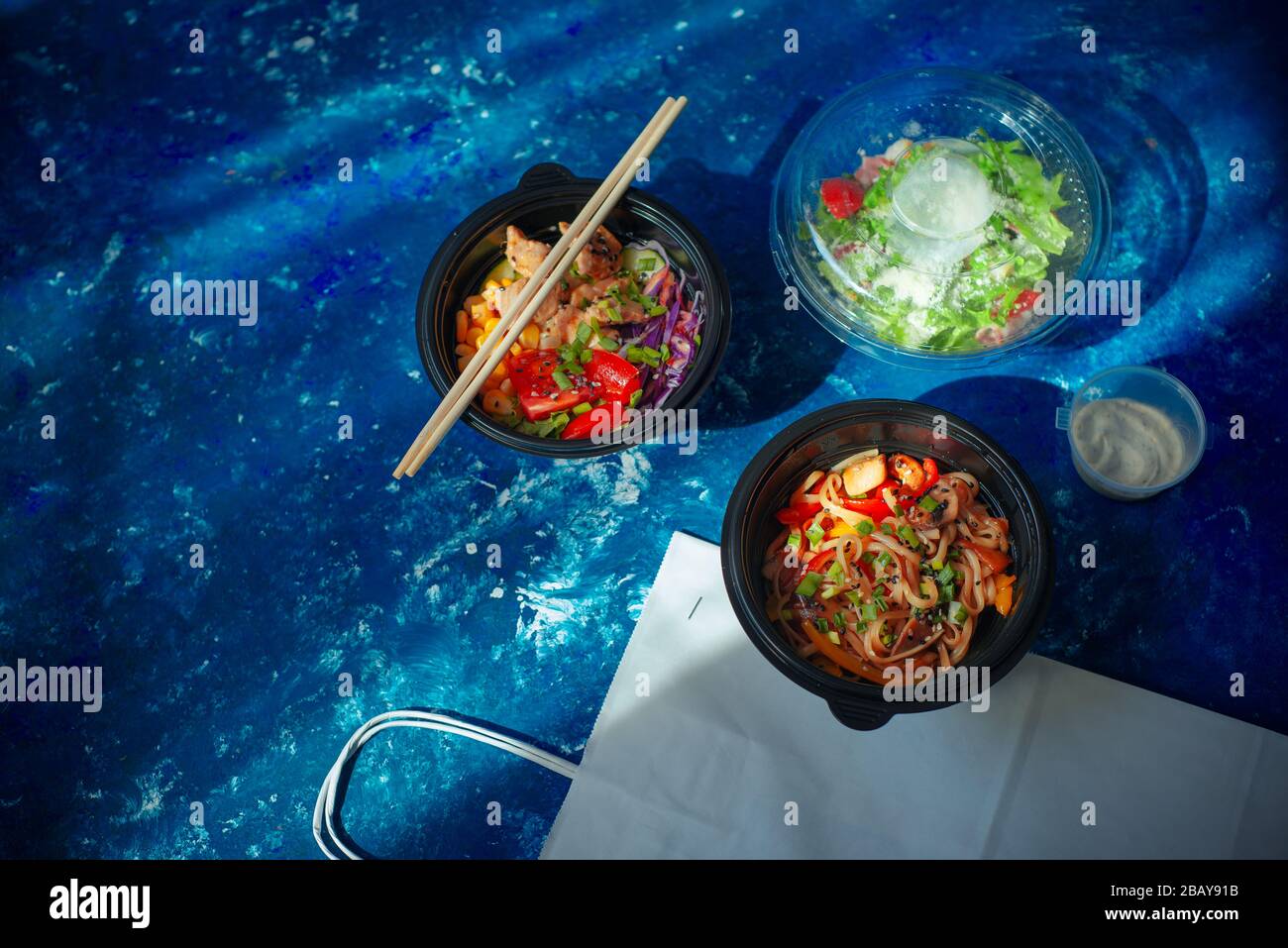 Prendere piatto con poke con pollo, udon e insalata di Ceasar in plastica Foto Stock