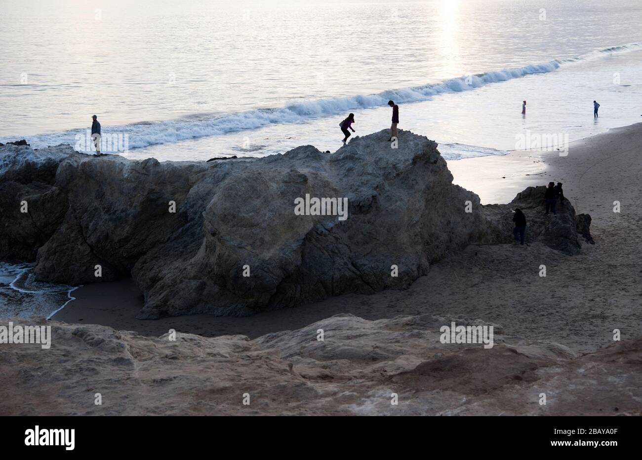 Persone che arrampicano su rocce sulla spiaggia vicino Malibu in California Foto Stock