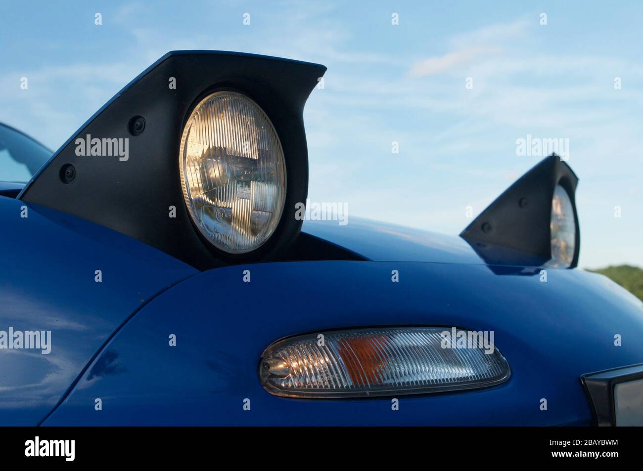 Primo piano dei fari a scomparsa, blu Mazda MX-5 mk1 Foto Stock