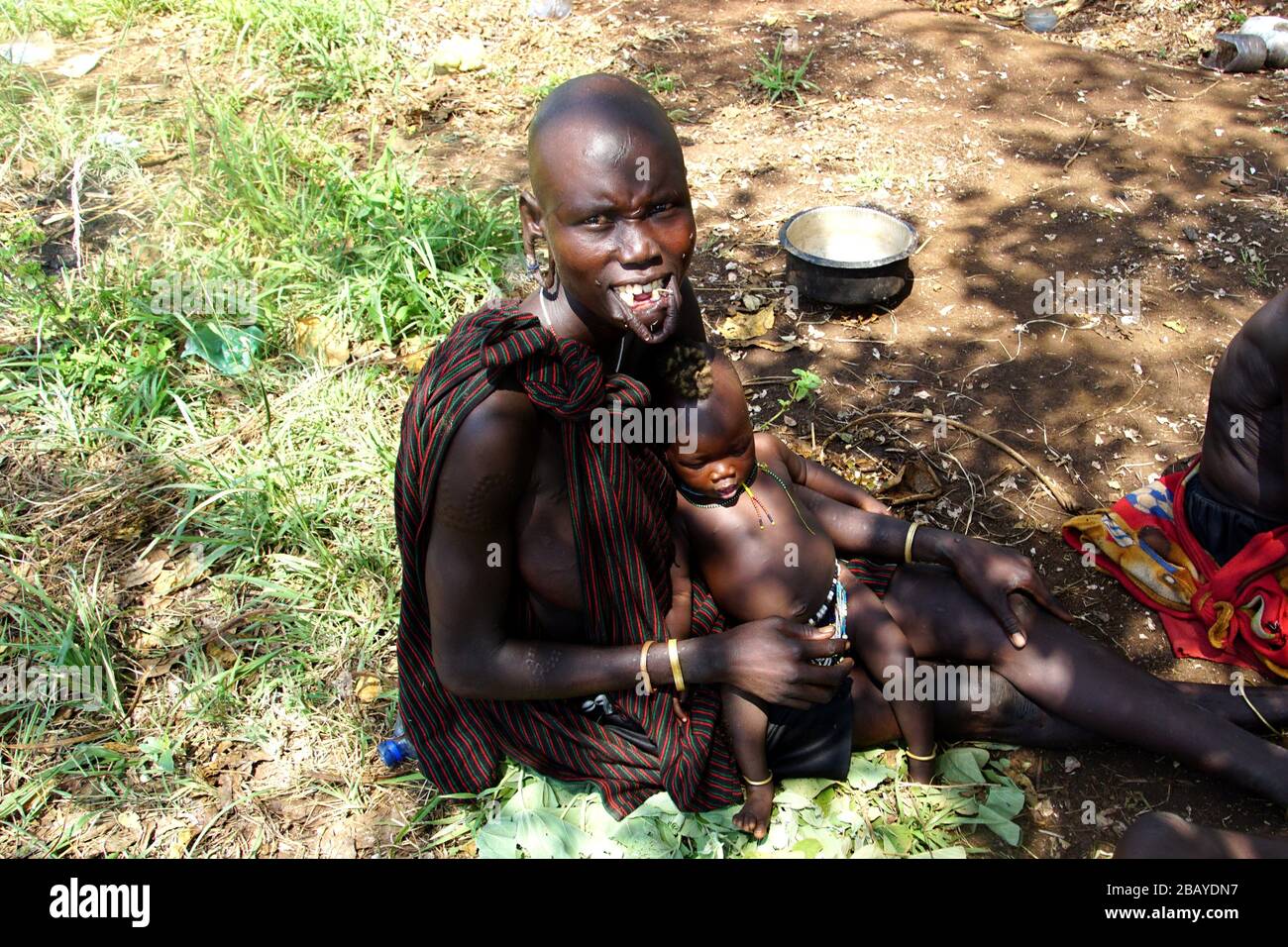 Mursi Tribe Mum senza labbro piastra culla il suo bambino nel suo giro Foto Stock