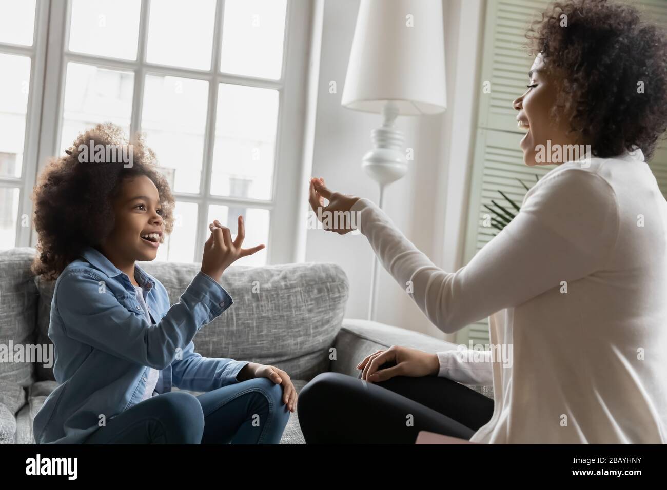 La piccola figlia africana che usa il linguaggio dei segni comunica con la madre Foto Stock