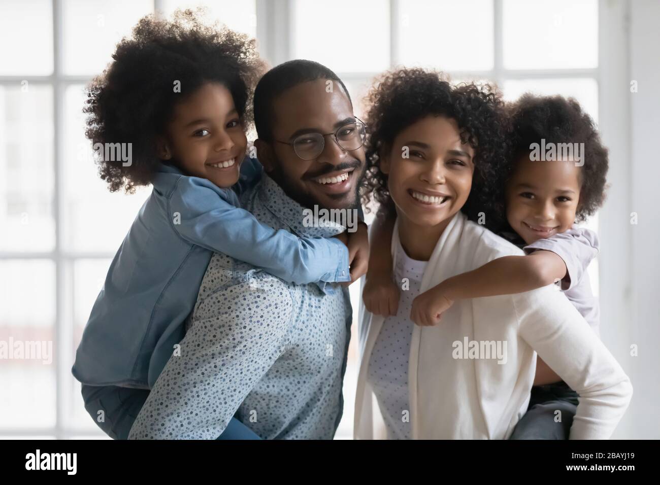 Ritratto di etnia africana genitori piggybacking figlio e figlia al chiuso Foto Stock