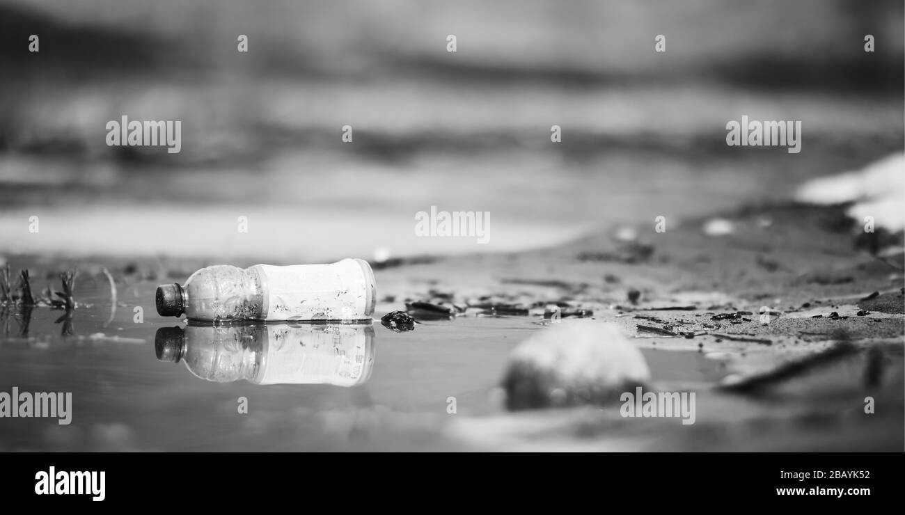 Abbandonato vuoto rosa bottiglia di plastica spazzatura al fiume banca conservancy inquinamento nero e bianco foto Foto Stock