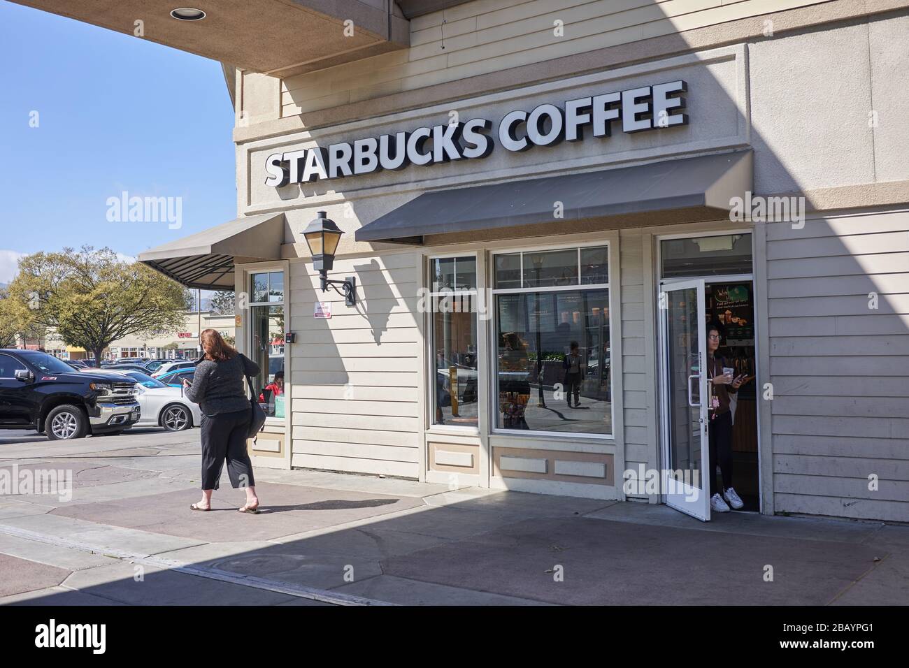 Una donna esce da una caffetteria Starbucks con una tazza da caffè da non fare a Redwood City, California. Foto Stock