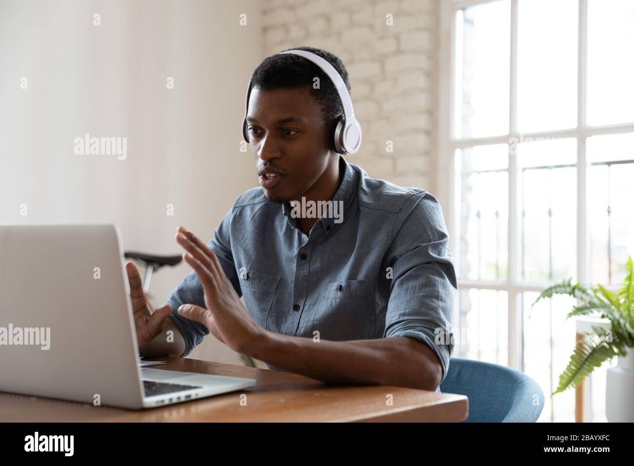 Responsabile africano che guarda lo schermo del laptop che parla con il cliente in modo distantante Foto Stock
