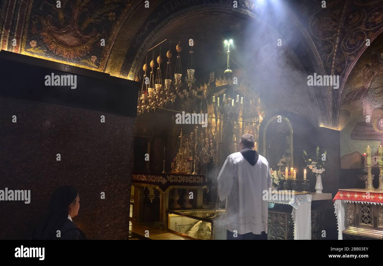 Sacerdote cattolico che celebra il servizio religioso all'interno della Chiesa del Santo Sepolcro. La Rocca di Calvario si può vedere sotto il vetro. Gerusalemme Foto Stock