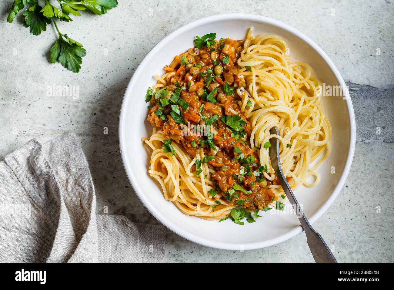 Lenticchie vegetariane alla bolognese con prezzemolo in un piatto bianco. Sano concetto di cibo vegano. Foto Stock