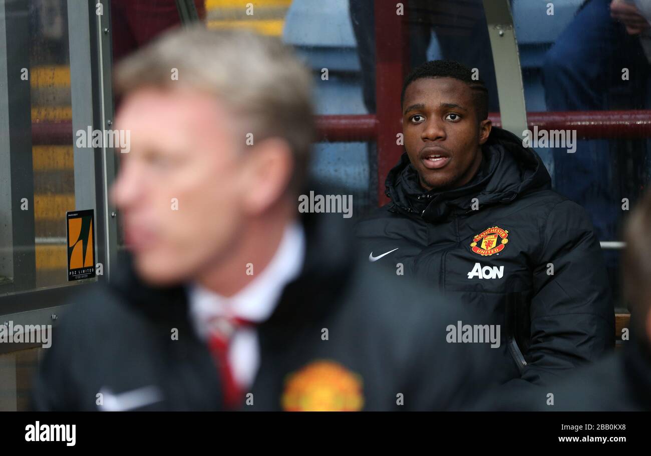 Wilfried Zaha del Manchester United siede dietro il direttore David Moyes sul banco dei sostituti Foto Stock