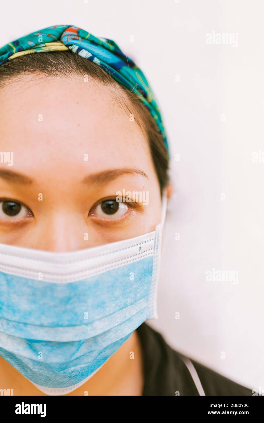 Tema del coronavirus. Donna asiatica che indossa una maschera per proteggersi da infettarsi su uno sfondo bianco. Foto Stock