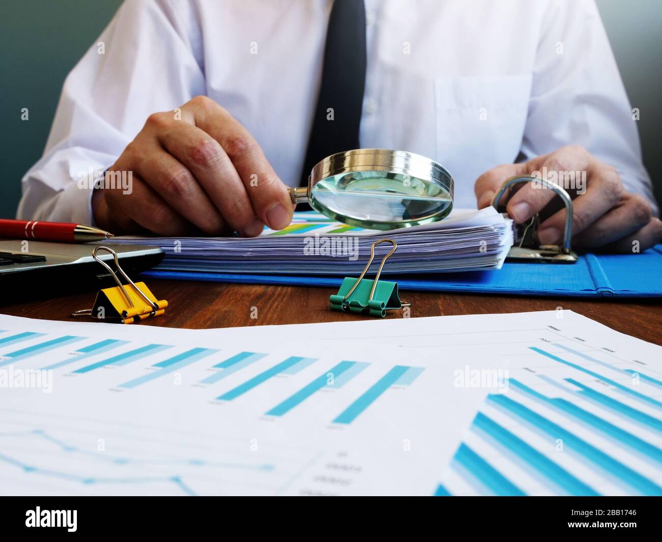 Auditor effettua un audit interno della società e controlla la relazione finanziaria con lente d'ingrandimento. Foto Stock