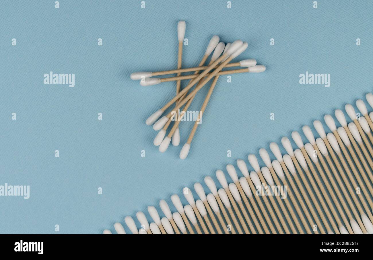 Composizione piatta con bastoncini di cotone su fondo blu. Bastoncini di cotone naturale in cotone e canna. Foto Stock