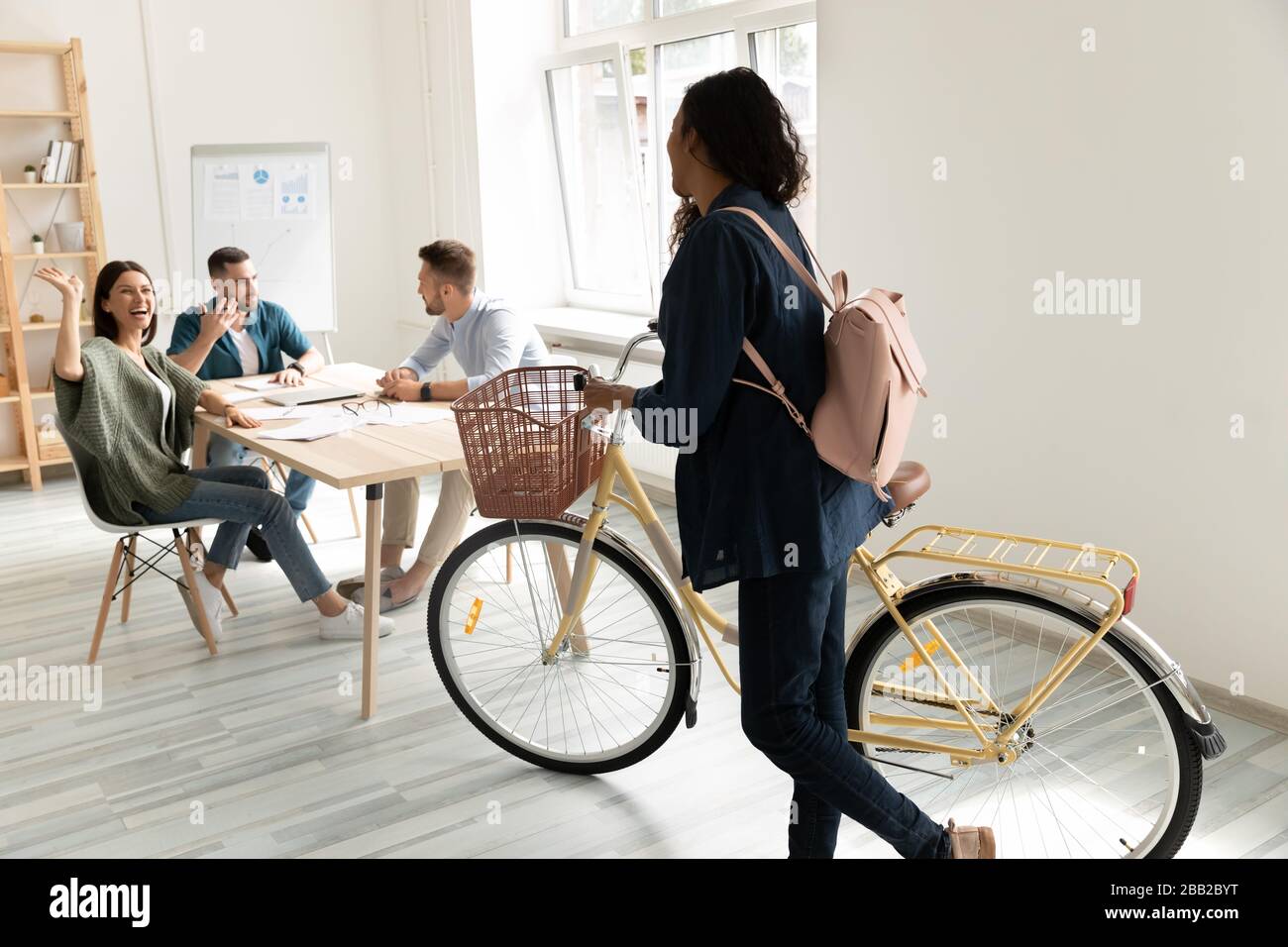 Biracial giovane donna di corsa dipendente bici in ufficio Foto Stock