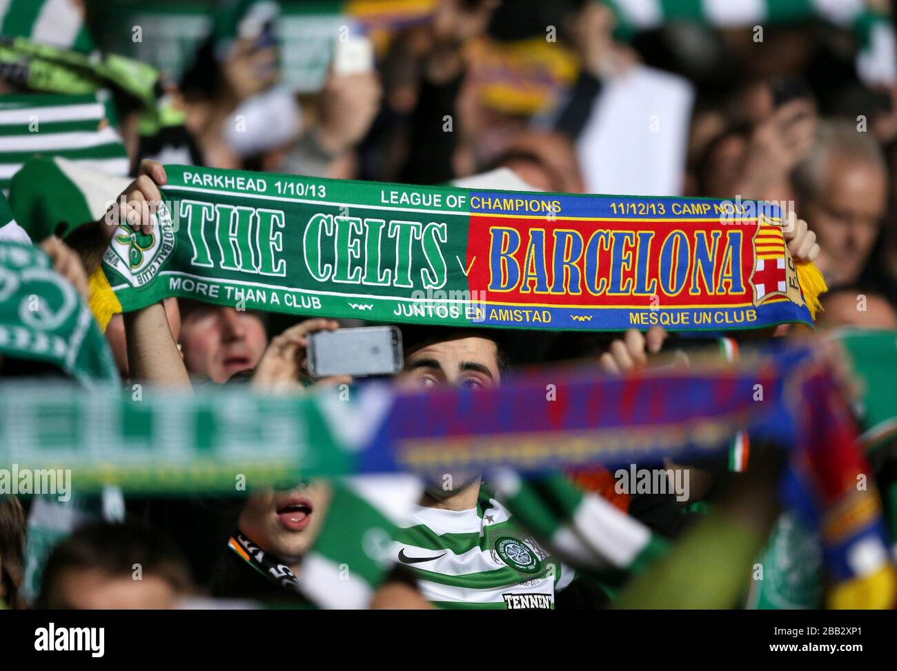 I ventilatori celtici tengono in su le sciarpe per mostrare il loro sostegno nelle tribune Foto Stock