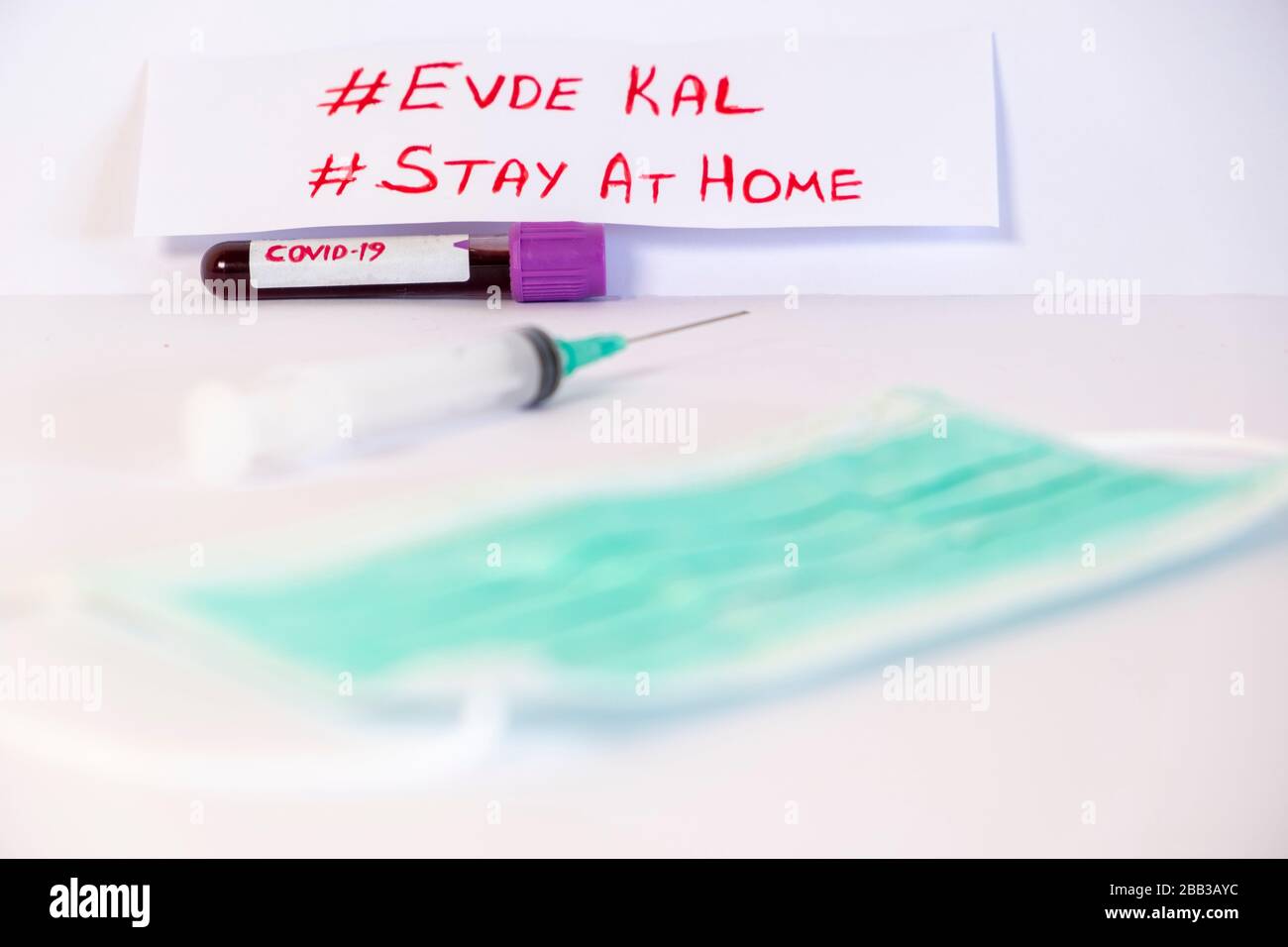 'Say a casa, evde kal'scrivendo su di esso, in inglese e turco. Provetta con campione di sangue per il test COVID-19 Foto Stock