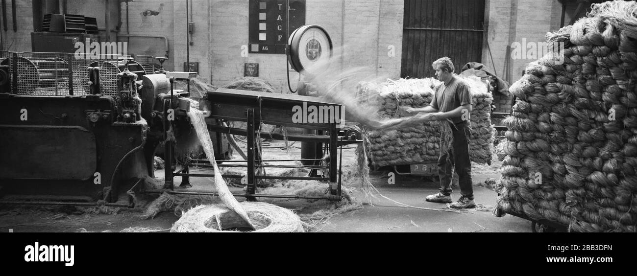 Un lavoratore che alimenta la iuta in una macchina al mulino di Tay Spinners a Dundee, in Scozia. Questo stabilimento è stato l'ultimo filatoio di iuta in Europa quando è stato chiuso per l'ultima volta nel 1998. La città di Dundee era stata famosa per la storia dei tre 'JS' - juta, jam e giornalismo. Foto Stock