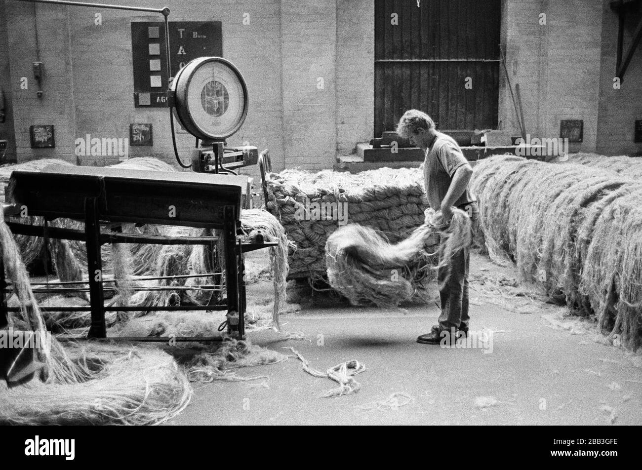 Un lavoratore che alimenta la iuta in una macchina al mulino di Tay Spinners a Dundee, in Scozia. Questo stabilimento è stato l'ultimo filatoio di iuta in Europa quando è stato chiuso per l'ultima volta nel 1998. La città di Dundee era stata famosa per la storia dei tre 'JS' - juta, jam e giornalismo. Foto Stock