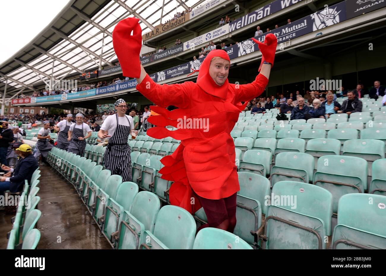 Un fan vestito come aragosta è inseguito da altri fan vestiti come Chefs in stand il giorno quattro della quinta prova Ashes al Kia Oval come la pioggia ritarda l'inizio del gioco Foto Stock