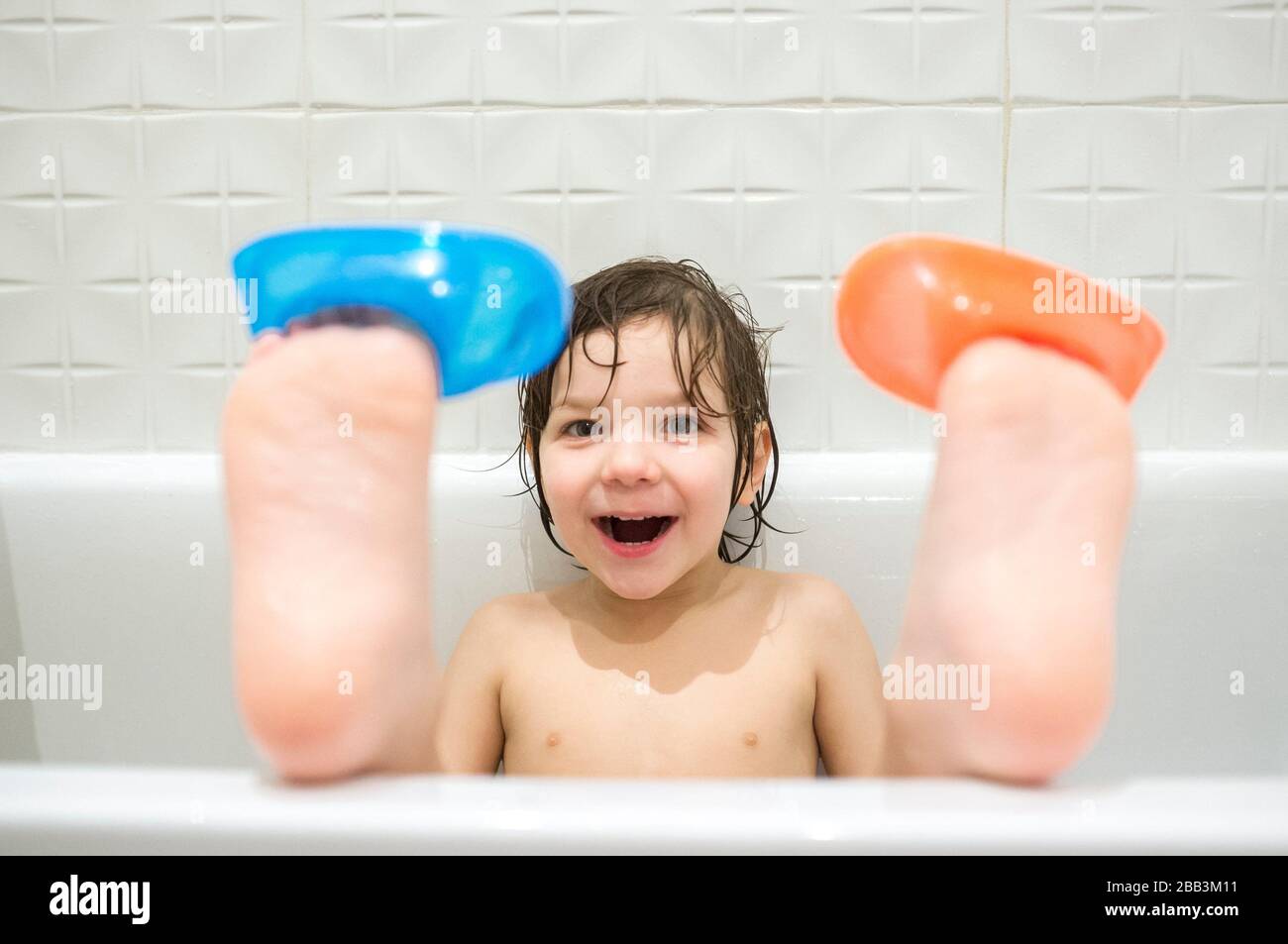 ragazzo di 4 anni che indossa le barche sulle dita dei piedi. I bambini si divertono nella vasca da bagno. Rumore dolce. Foto Stock