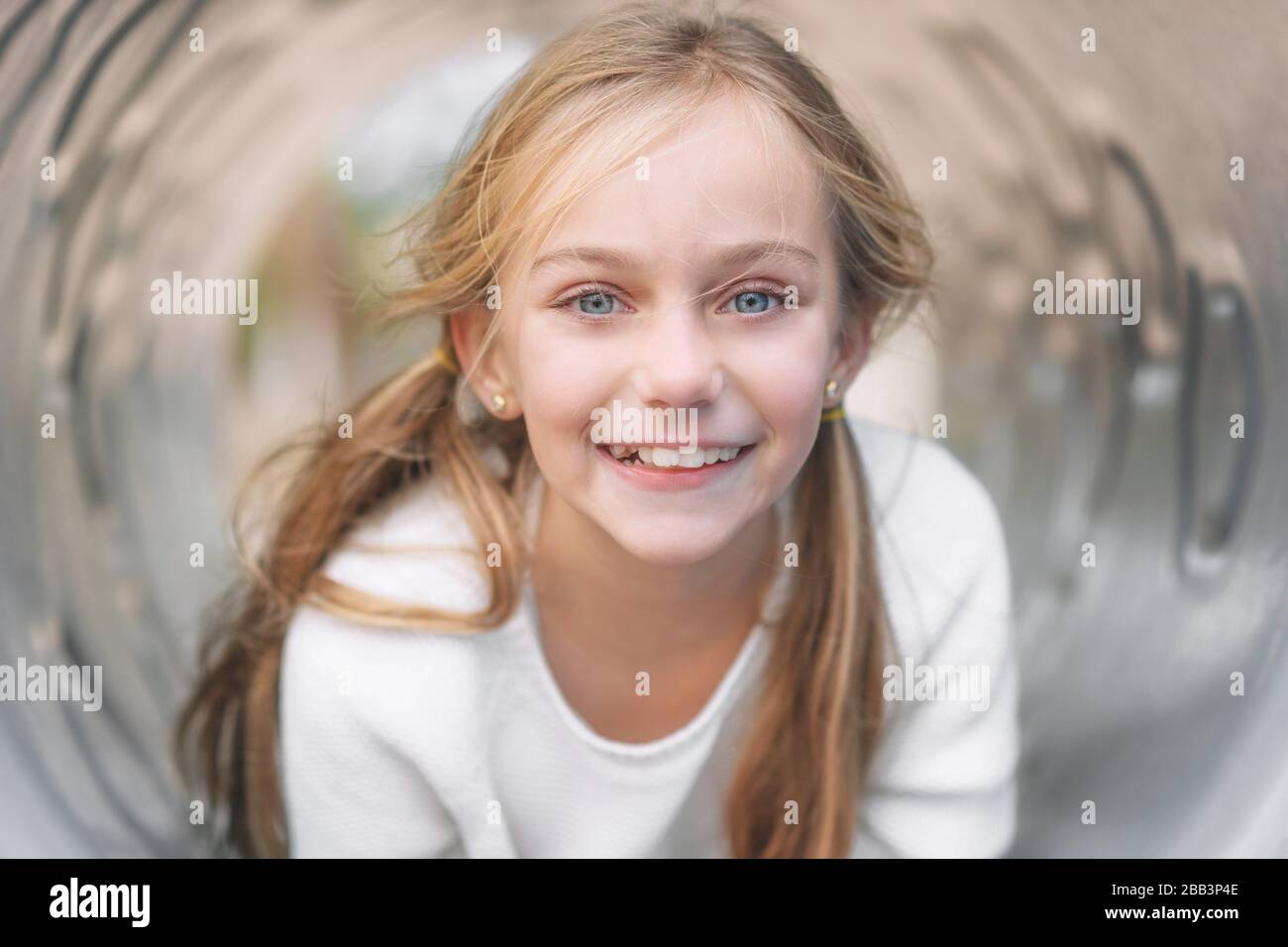 Bella, bambina, divertirsi, sdraiata su pipa sul parco giochi per bambini. Foto Stock