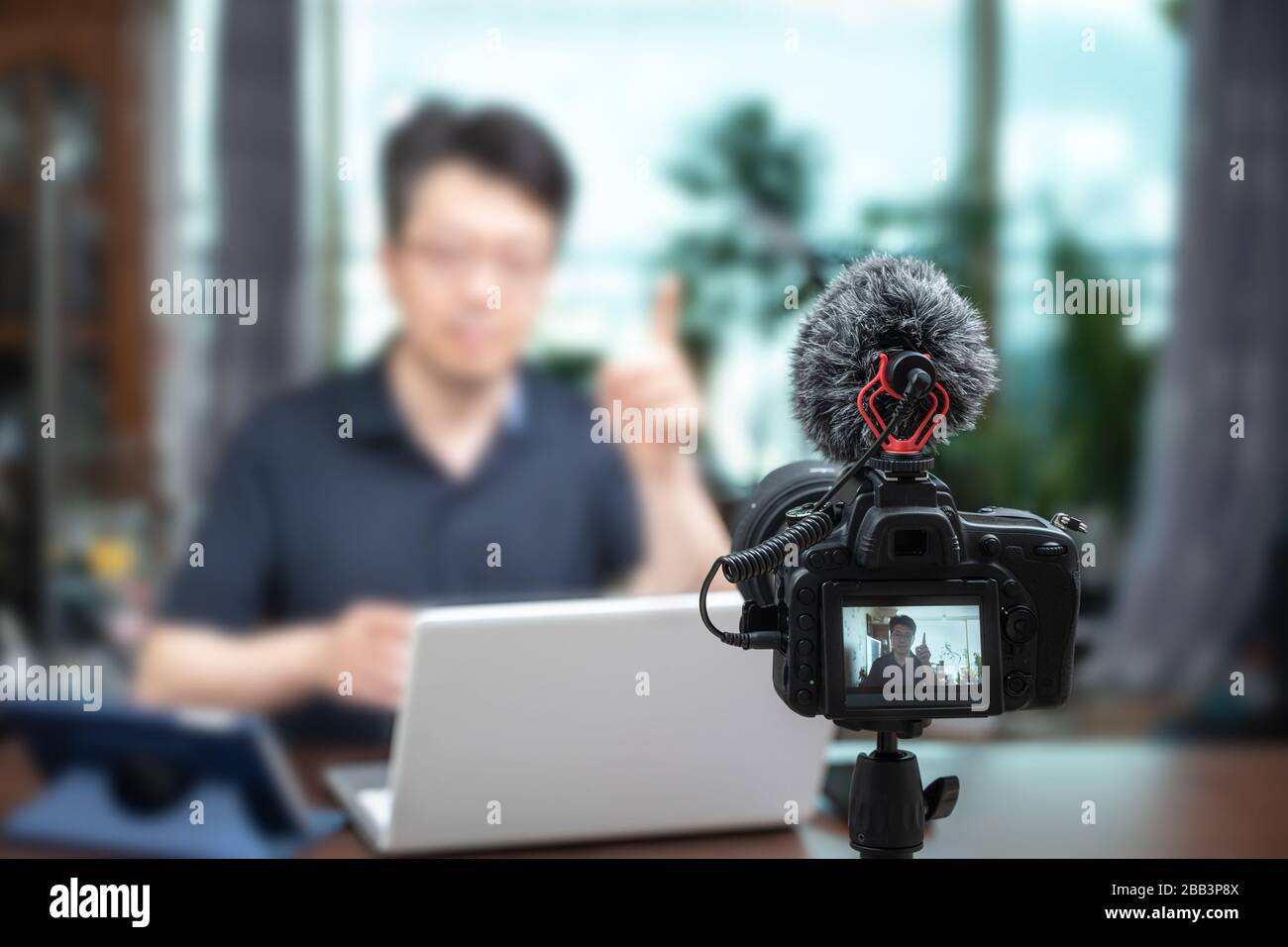 Concetto di conferenza online. Uomo asiatico di mezza età che offre lezioni online a casa. Sfocare lo sfondo Foto Stock