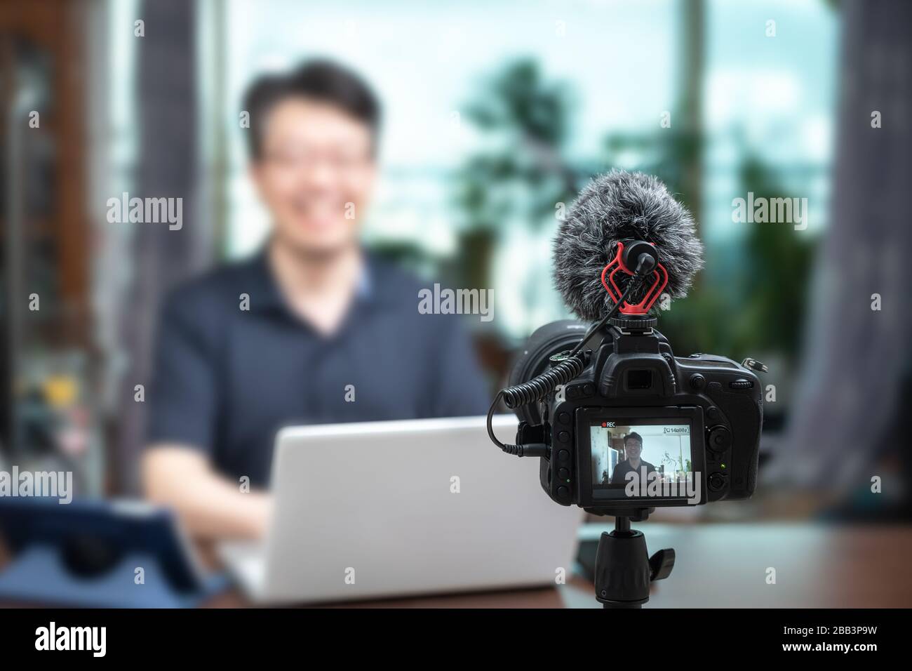 Concetto di conferenza online. Uomo asiatico di mezza età che offre lezioni online a casa. Sfocare lo sfondo Foto Stock