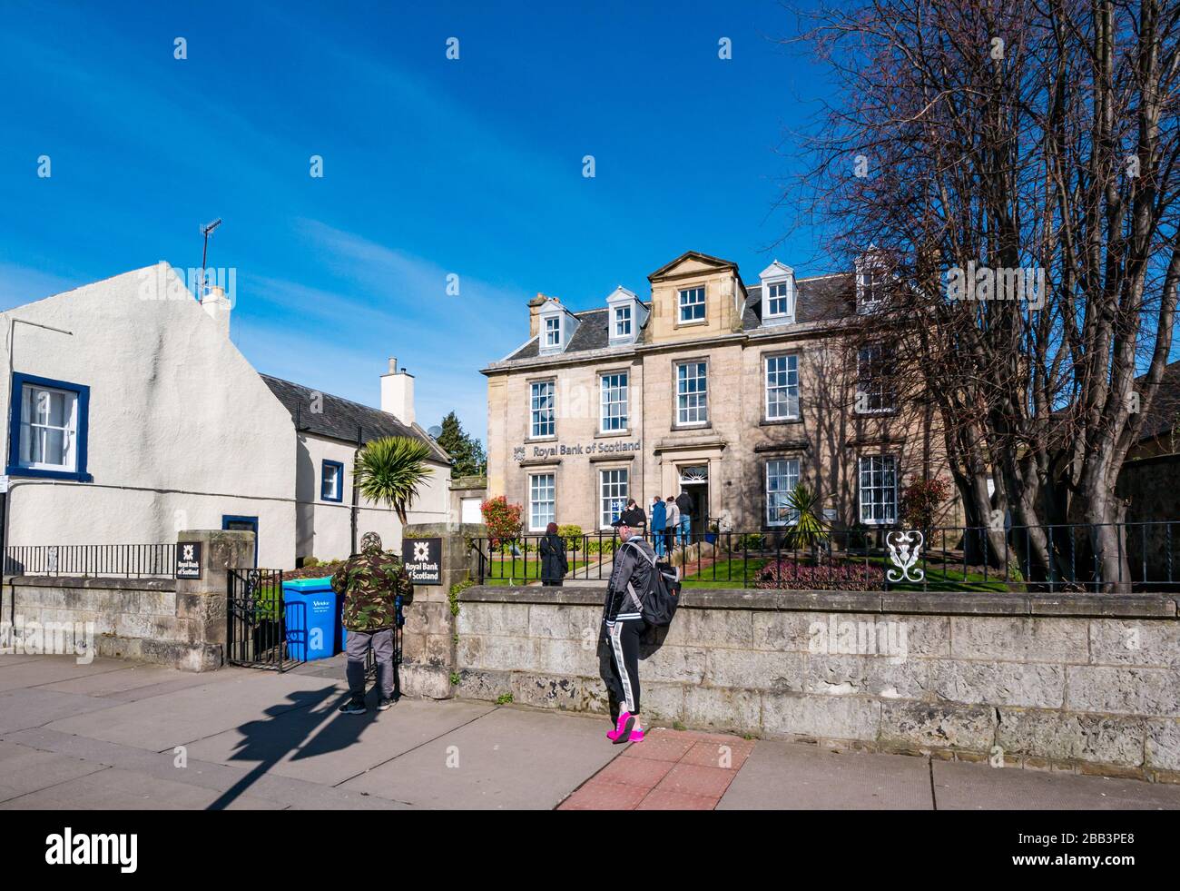 Haddington, East Lothian, Scozia, Regno Unito, 30th marzo 2020. Covid-19 Coronavirus ha un impatto sulla città di mercato normalmente vivace in una bella giornata di primavera con strade vuote e persone che si distende sociale. La gente fila fuori di una filiale della Royal Bank of Scotland che mantiene 2m a parte Foto Stock