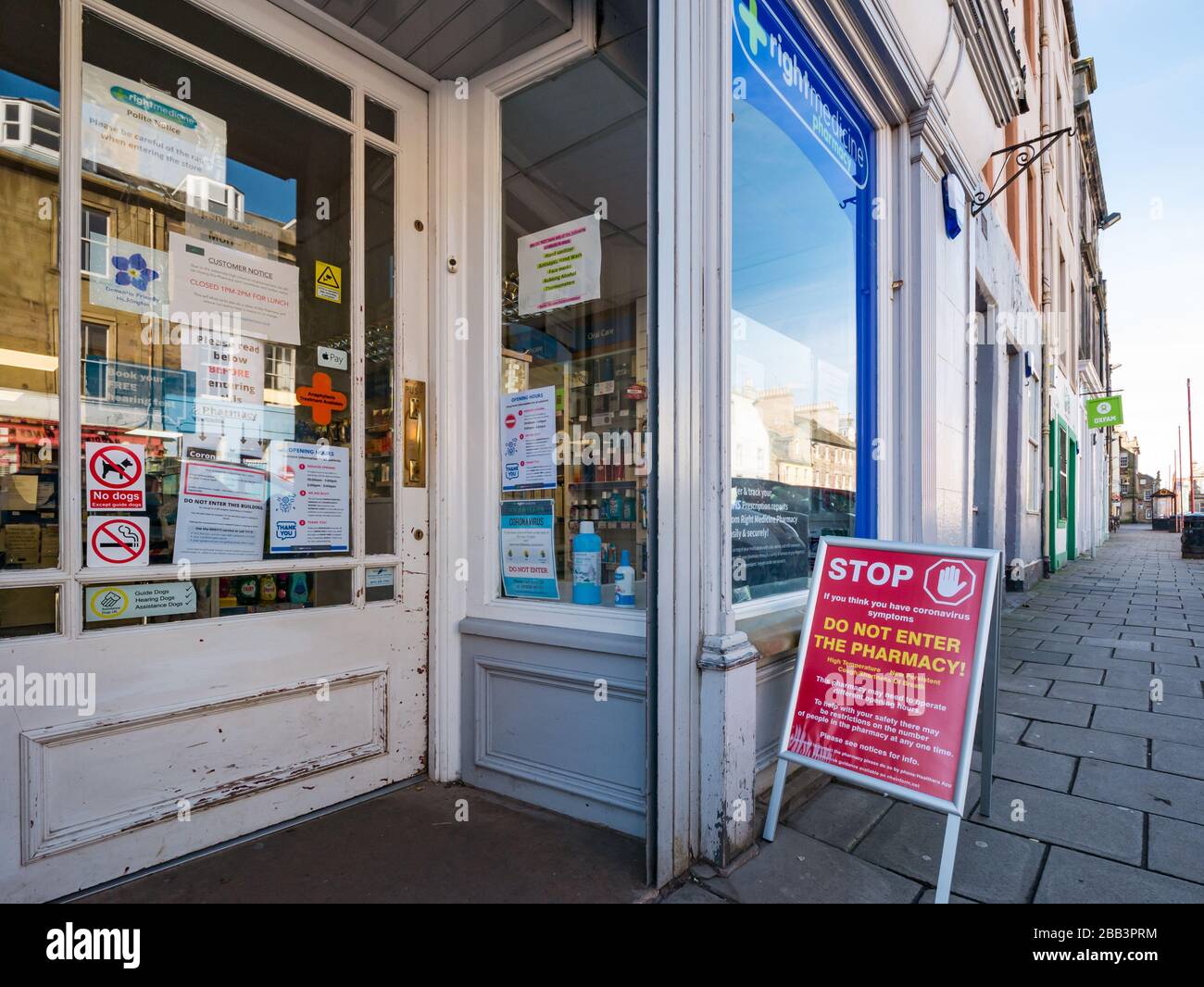 Haddington, East Lothian, Scozia, Regno Unito. 30th marzo 2020. Covid-19 Coronavirus ha un impatto sulla città di mercato normalmente vivace in una bella giornata di primavera con strade vuote e persone che si distende sociale. Un avviso al di fuori di una farmacia locale che avverte la gente di non entrare Foto Stock