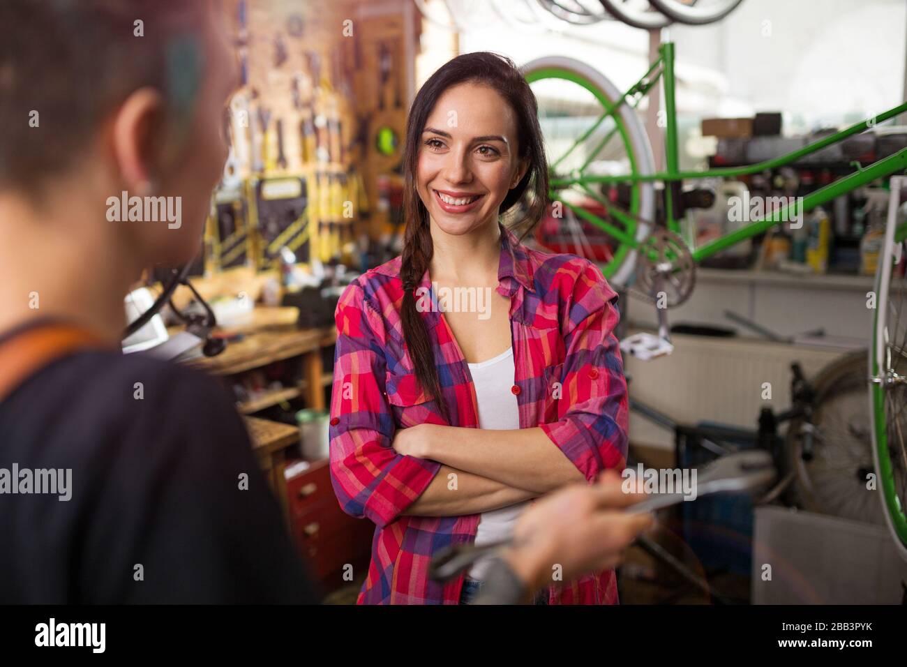Due giovani donne che lavorano in un negozio di riparazione di biciclette Foto Stock