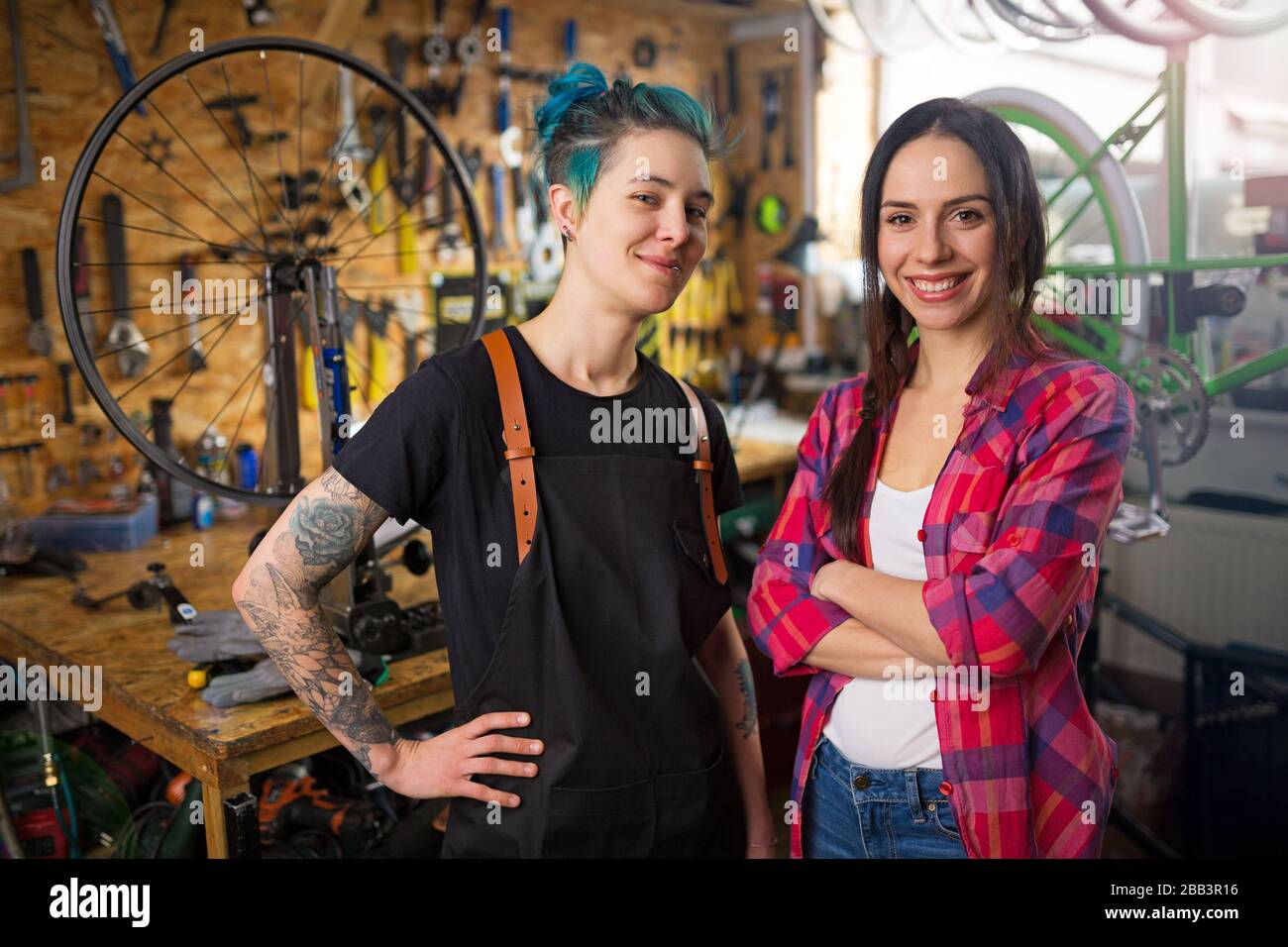 Due giovani donne che lavorano in un negozio di riparazione di biciclette Foto Stock