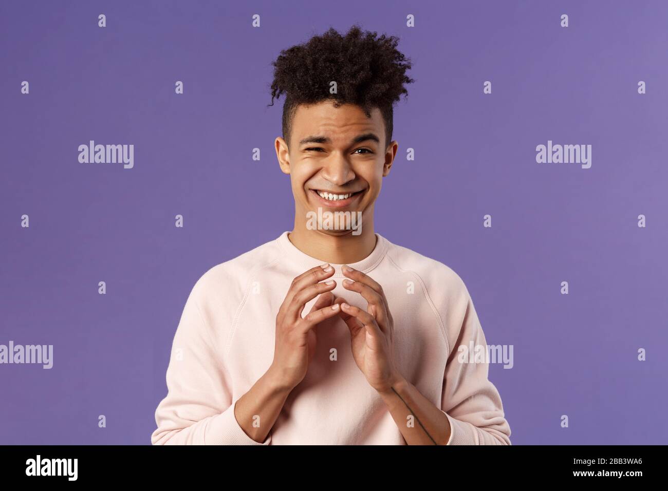 Ritratto di un giovane creativo intelligente con dreads, dita acciaiose vicino al petto e smirk devioso, hanno un piano perfetto, schematizzato qualcosa per gli stolti di aprile Foto Stock