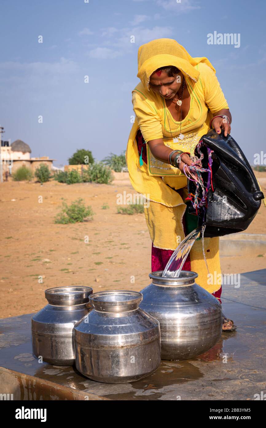 Donna che raccoglie l'acqua da una comunità bene, deserto di Thar, Rajasthan, India Foto Stock