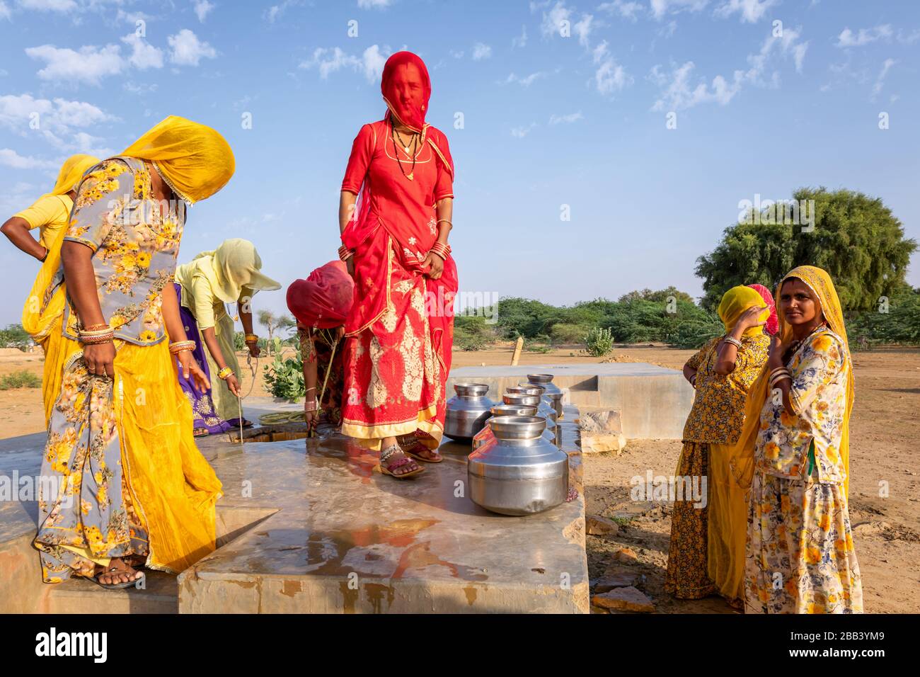 Donne che raccolgono l'acqua da una comunità bene, deserto di Thar, Rajasthan, India Foto Stock