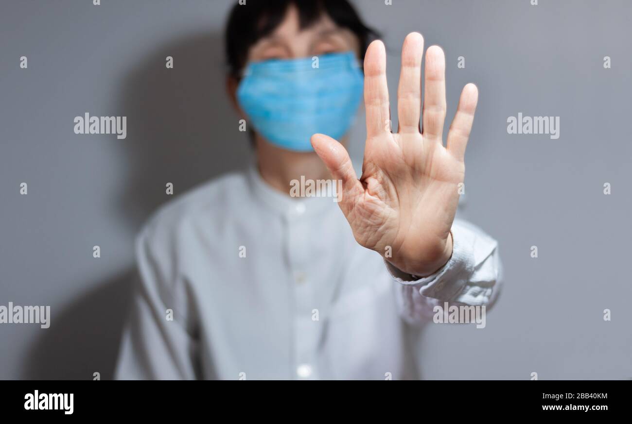 Arrestare la quarantena del coronavirus e il concetto di inquinamento atmosferico pm2.5. Donna anziana malata che indossa maschera respiratore per proteggere con braccio allungato. Wuhan, Cina ep Foto Stock