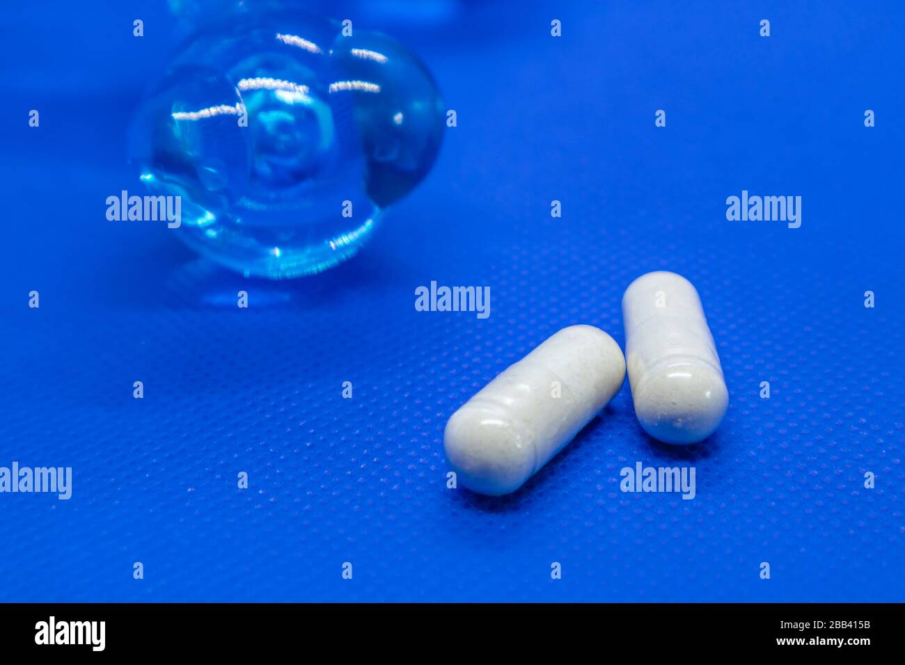 Capsule lunghe bianche supplemento pillole su sfondo blu. Cure medicina salute farmaco vivido colori vibranti macro isolato primo piano Foto Stock