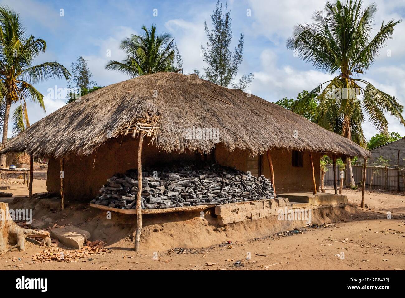 Casa tradizionale mozambicana costruita da bambù, fango e erba che si chatching. Carbone di cottura è accatastato su portico. Foto Stock