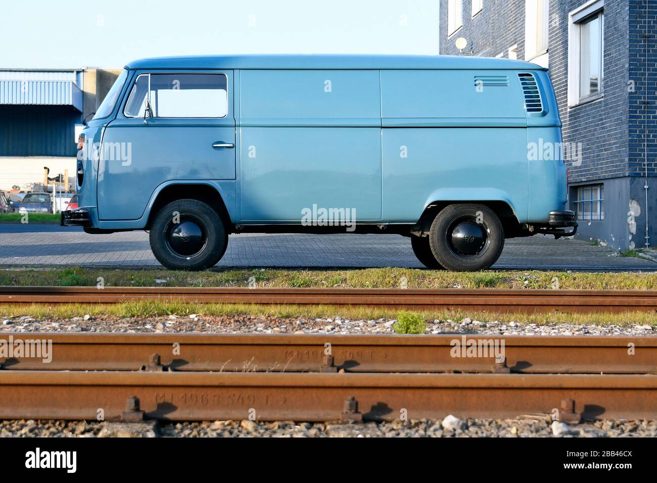 Bus VW azzurro accanto alle rotaie nel porto di spedizione di Düsseldorf . Foto Stock