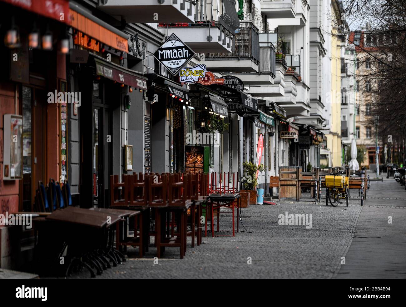 Berlino, Germania. 27th Mar, 2020. I bar e i ristoranti della Simon-Dach-Strasse, altrimenti affollata, a Berlino-Friedrichshain sono chiusi a causa della pandemia della Corona, e solo una bicicletta per ufficio postale si trova sul marciapiede altrimenti vuoto. Credito: Britta Pedersen/dpa-Zentralbild/dpa/Alamy Live News Foto Stock