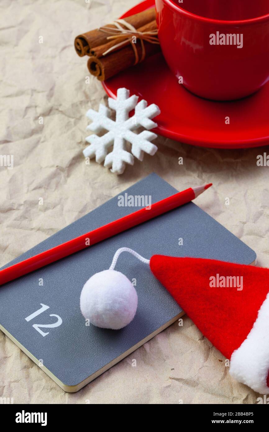 Foto della tazza rossa di caffè, diario con matita rossa. Piani per dicembre. Vicino diario Babbo Natale cap. Vacanze invernali. buon natale e felice nuovo yea Foto Stock