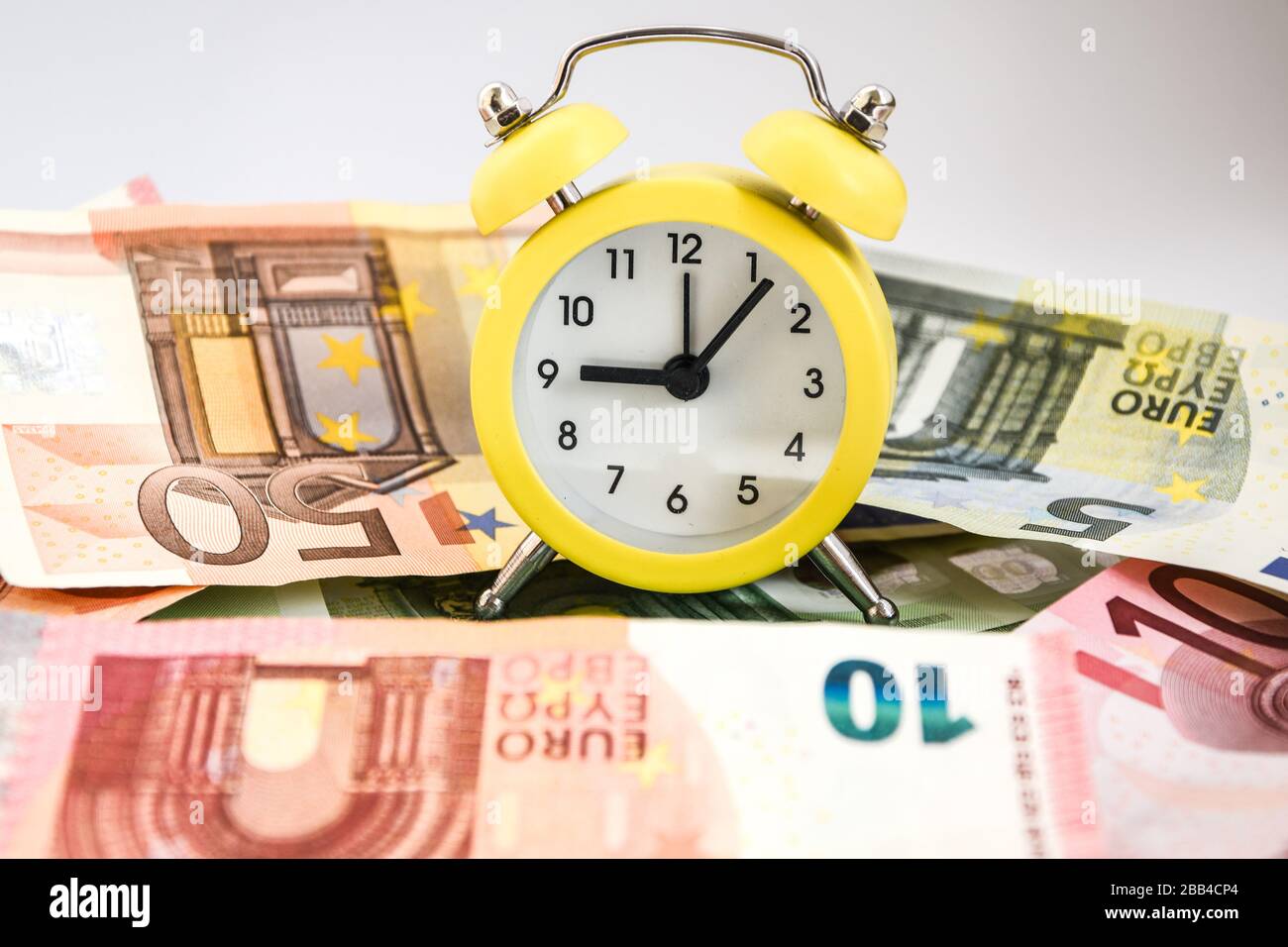 Il tempo è denaro. Stima europea del vostro tempo. Evro, sveglia, e carta europea moneta, su sfondo bianco. Concetto di business, il tempo è denaro Foto Stock