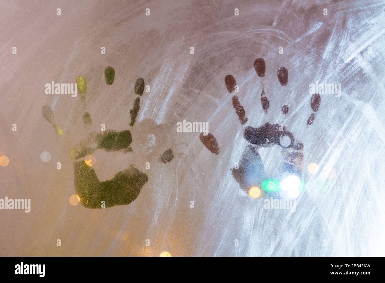 Due stampe a mano di bambino bambino in condensazione sul vetro della finestra di notte con bokeh di luci della strada Foto Stock