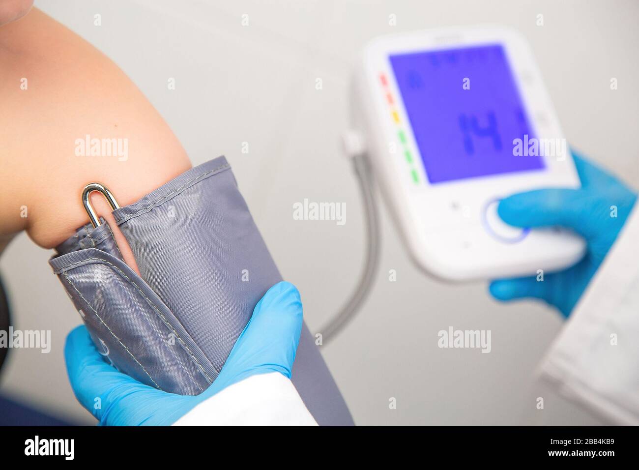 Ritratto di infermiere che prende la pressione sanguigna di un bambino con un monitor elettronico della pressione sanguigna Foto Stock