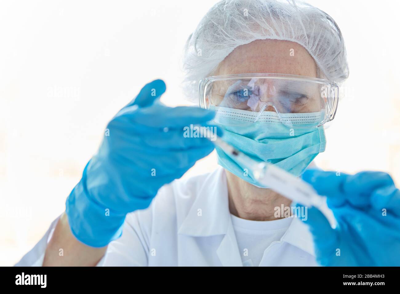 Ricercatori che utilizzano siringhe con vaccino contro Covid-19 in laboratorio durante un'epidemia di coronavirus Foto Stock